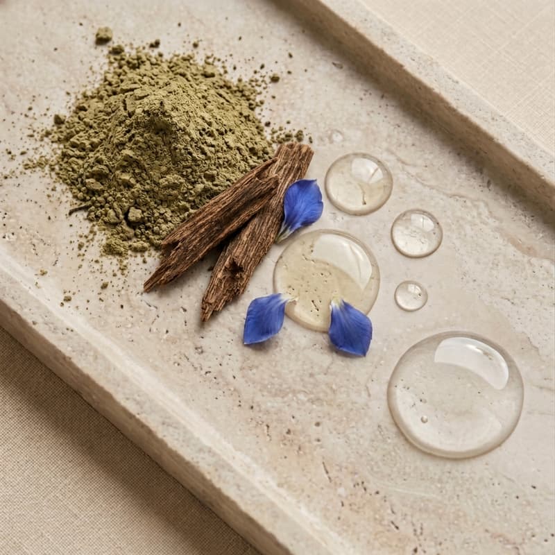 Composition de poudre verte, morceaux de bois, pétales et gouttes de gel sur un plateau en pierre.